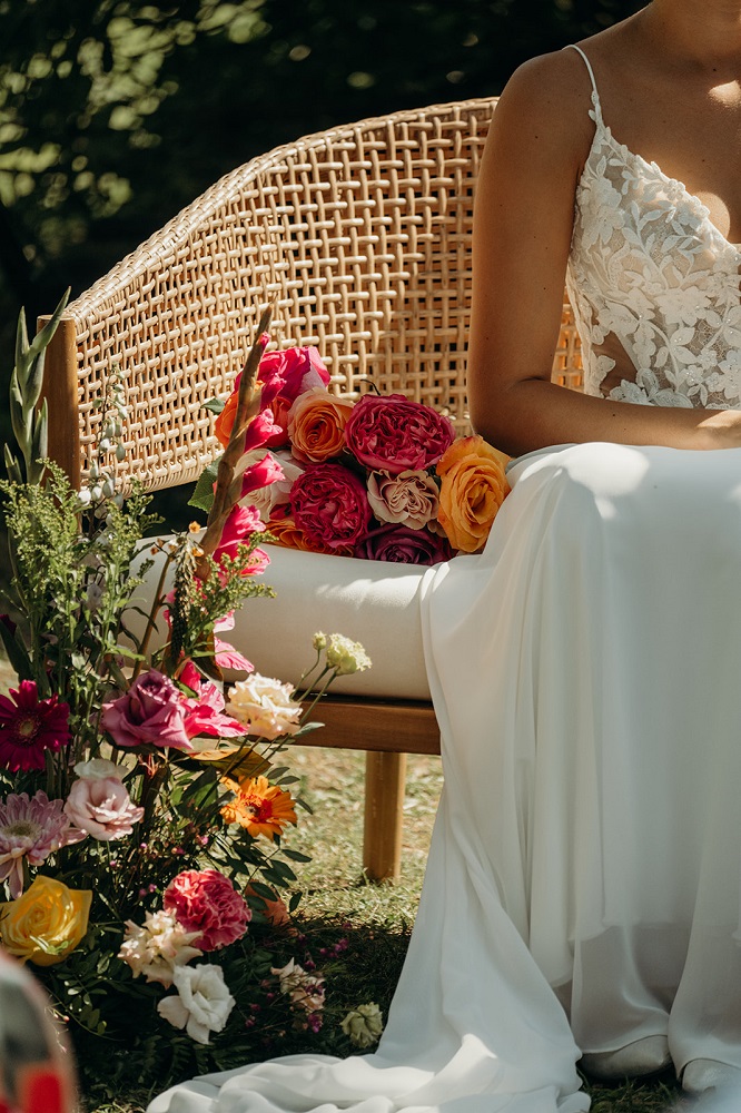Mariée posant sur une banquette de mariage avec bouquet à côté et fleurs au sol