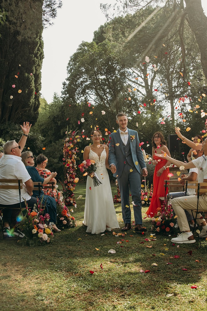 Invités d'un mariage lançant des pétales sur le couple