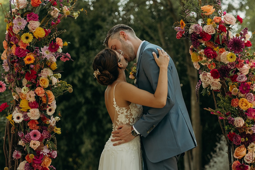 Jeunes mariés s'embrassant devant l'arche de cérémonie de mariage