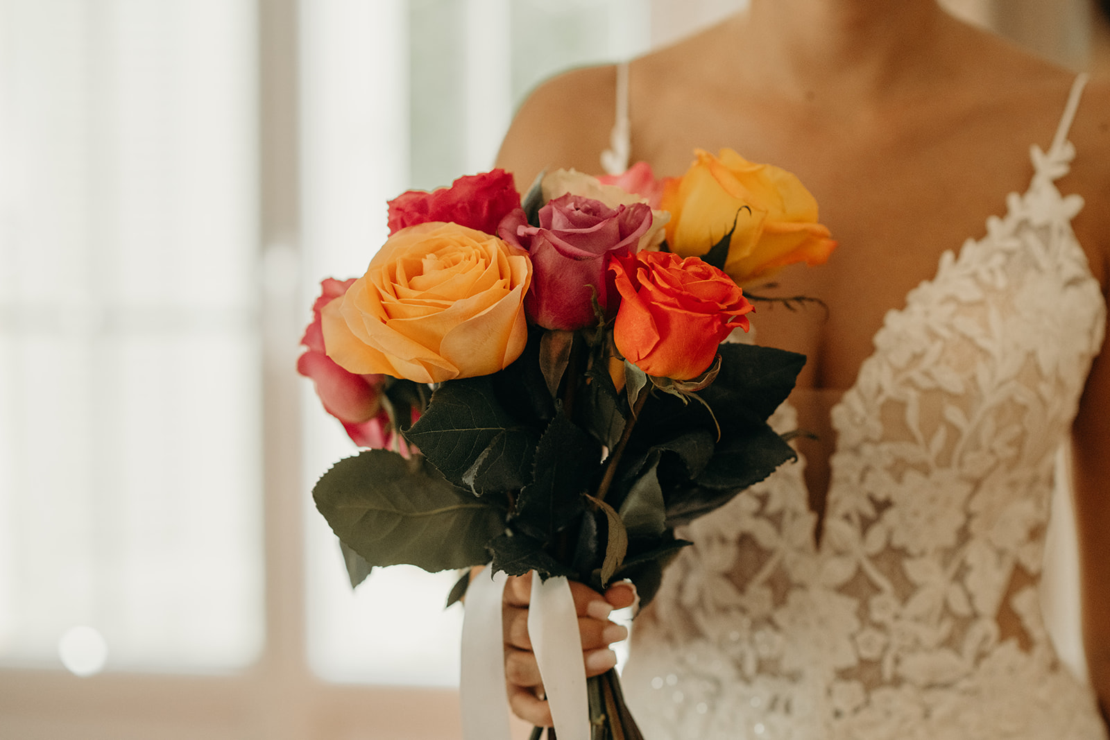 Mariée tenant un bouquet de roses colorées