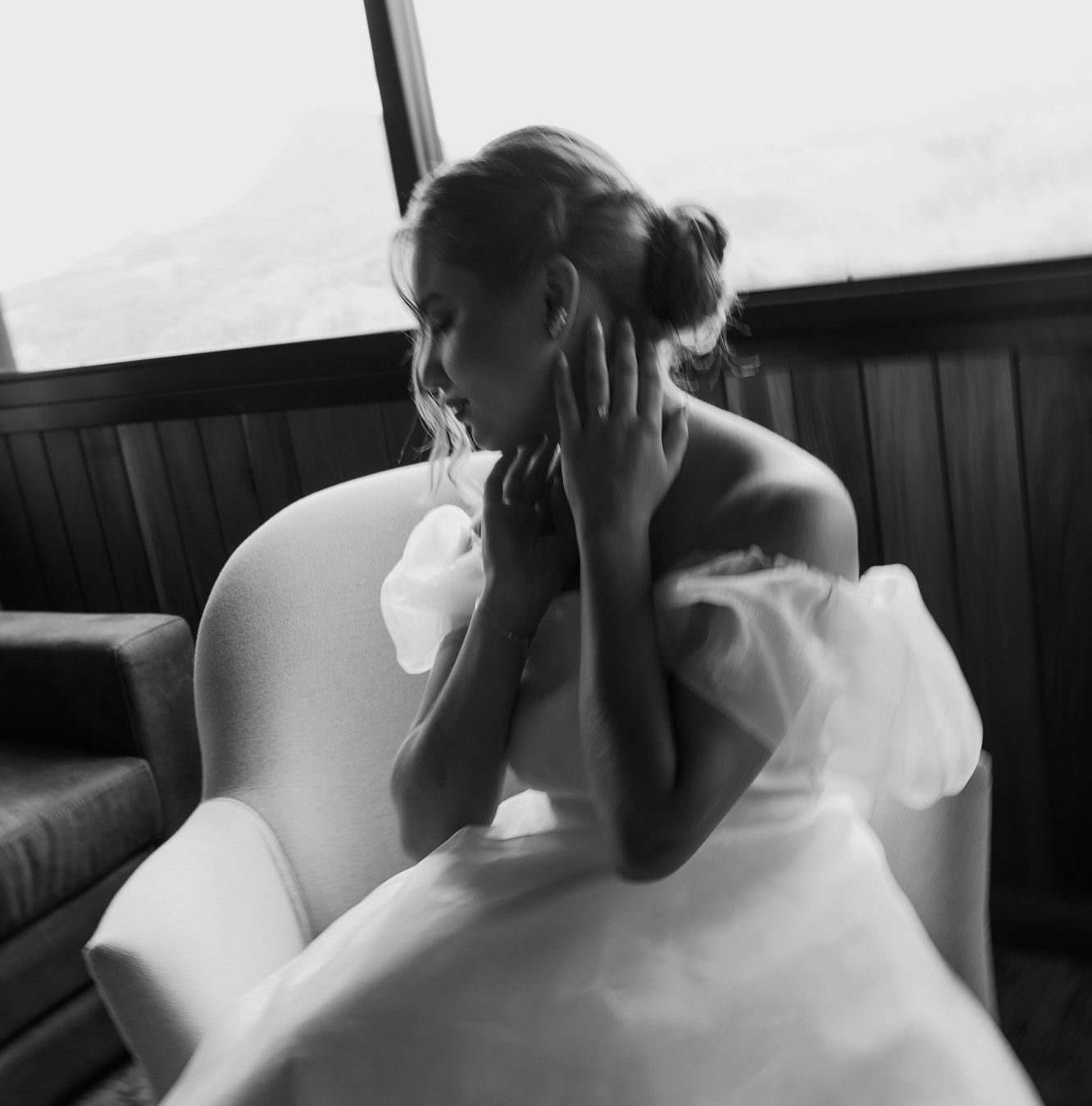 Mariée en robe assise sur un fauteuil, une main sur son cou