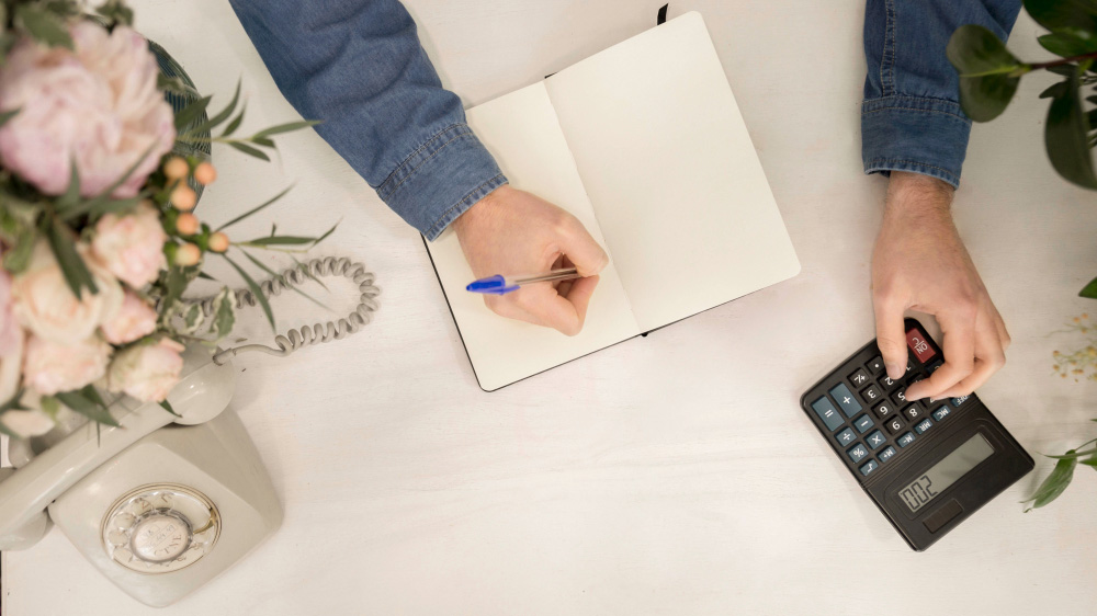 futurs mariés calculant le budget de leur mariage Couple de futurs mariés calculant le budget de leur mariage devant un carnet et une calculatrice